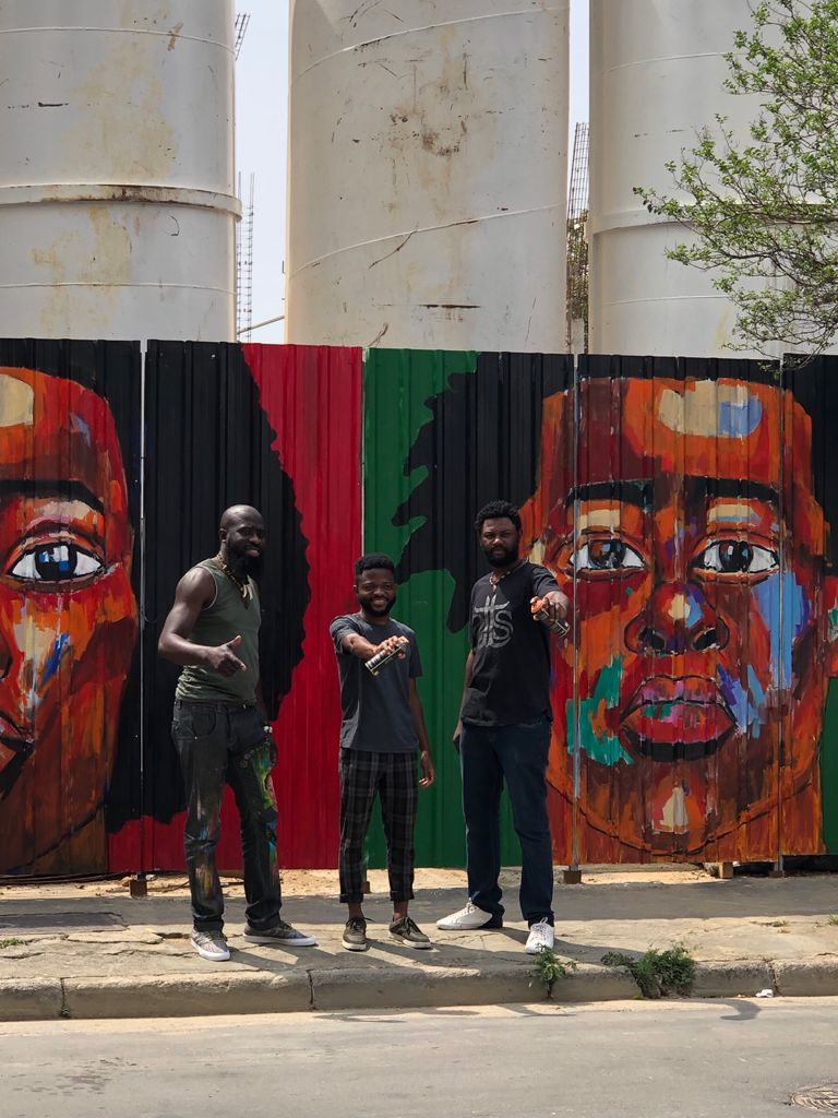 artists sitting in front of the painting